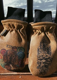 two brown mittens with designs on them