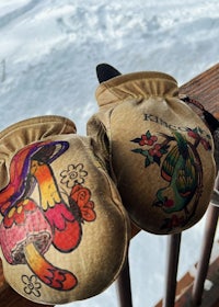 two mittens with tattoos on them sitting on a railing